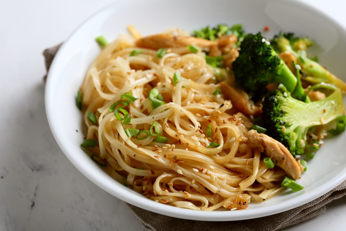 A plate of noodles with fresh scallions and broccoli