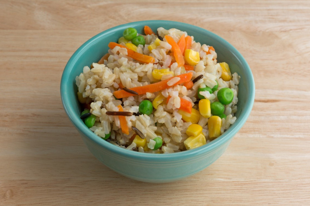 A bowl of rice with different colorful vegetables