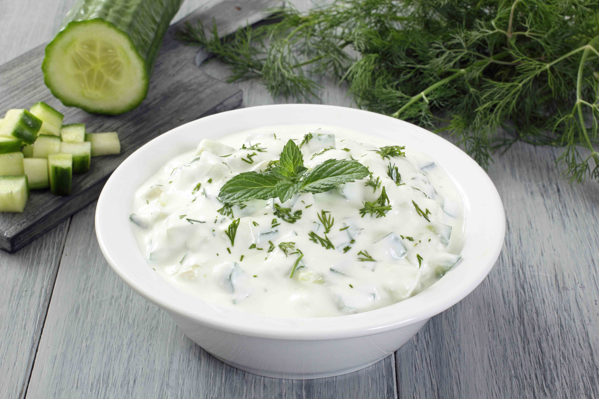 A bowl of cucumber yogurt dip topped with herbs