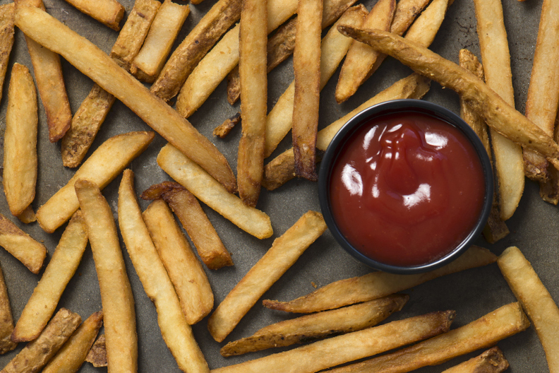 A tray of French fries with a side of ketchup