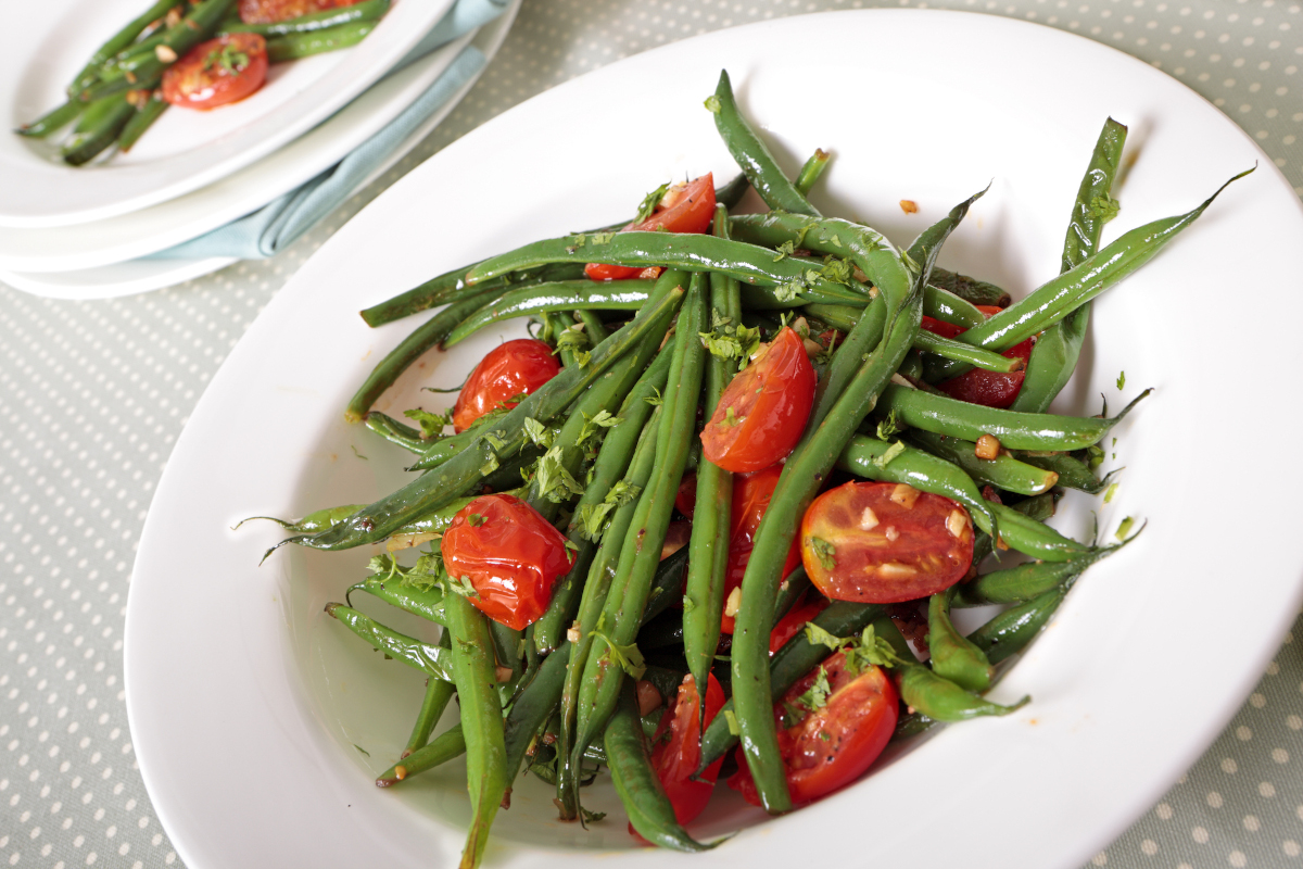 A bowl of green beans and halved cherry tomatoes