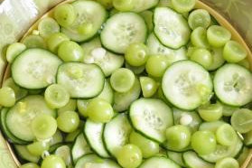 A bowl green grapes and sliced cucumbers