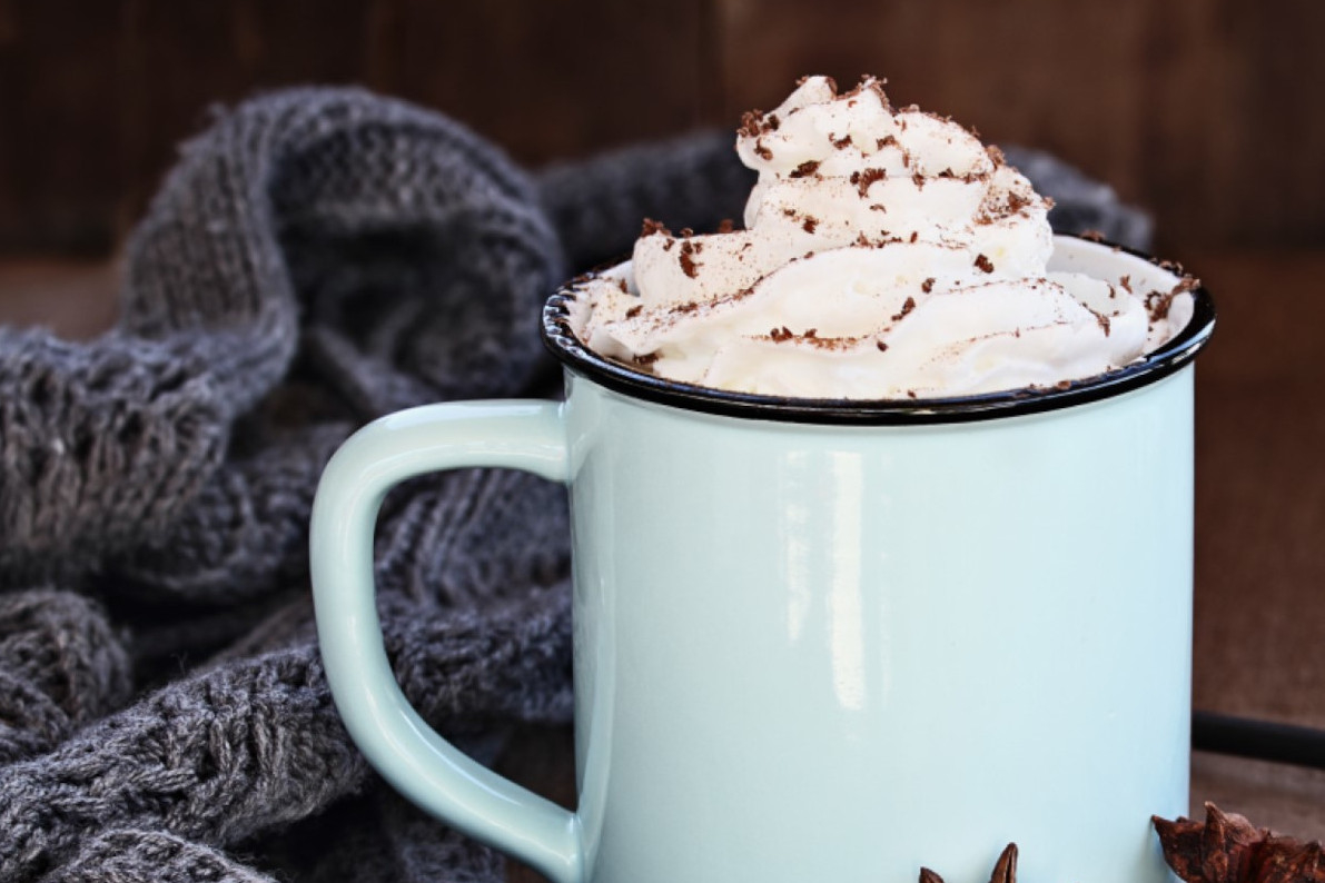 A blue coffee mug topped with whipped cream