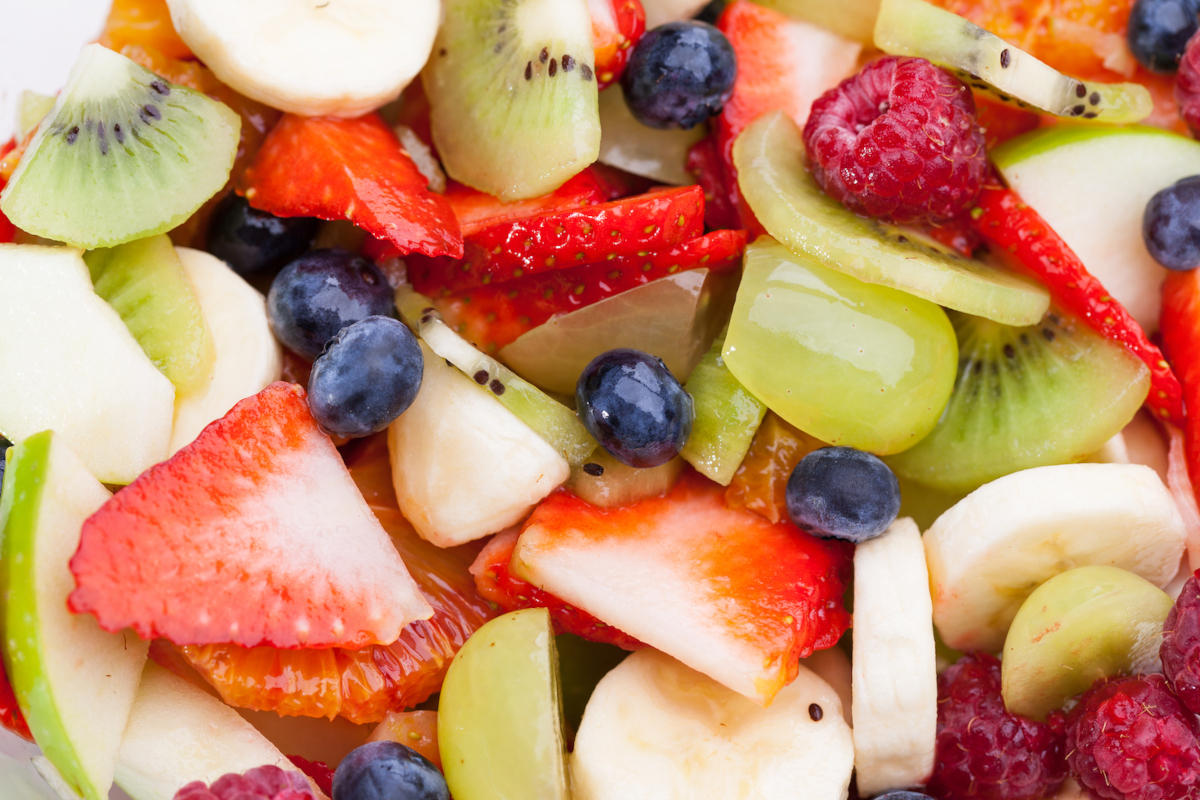 A mixture of sliced strawberries, green applies, bananas, raspberries, kiwis, grapes and blueberries