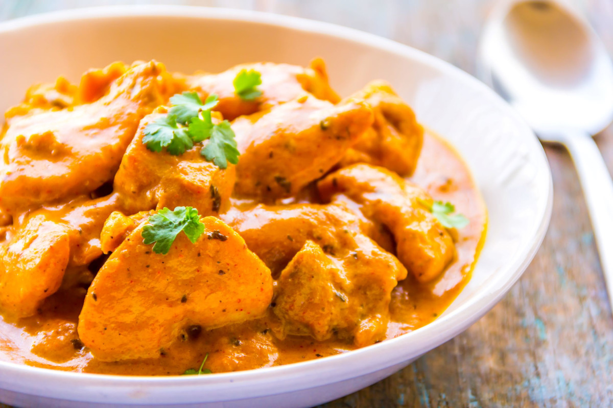 A bowl of chicken in an orange curry sauce