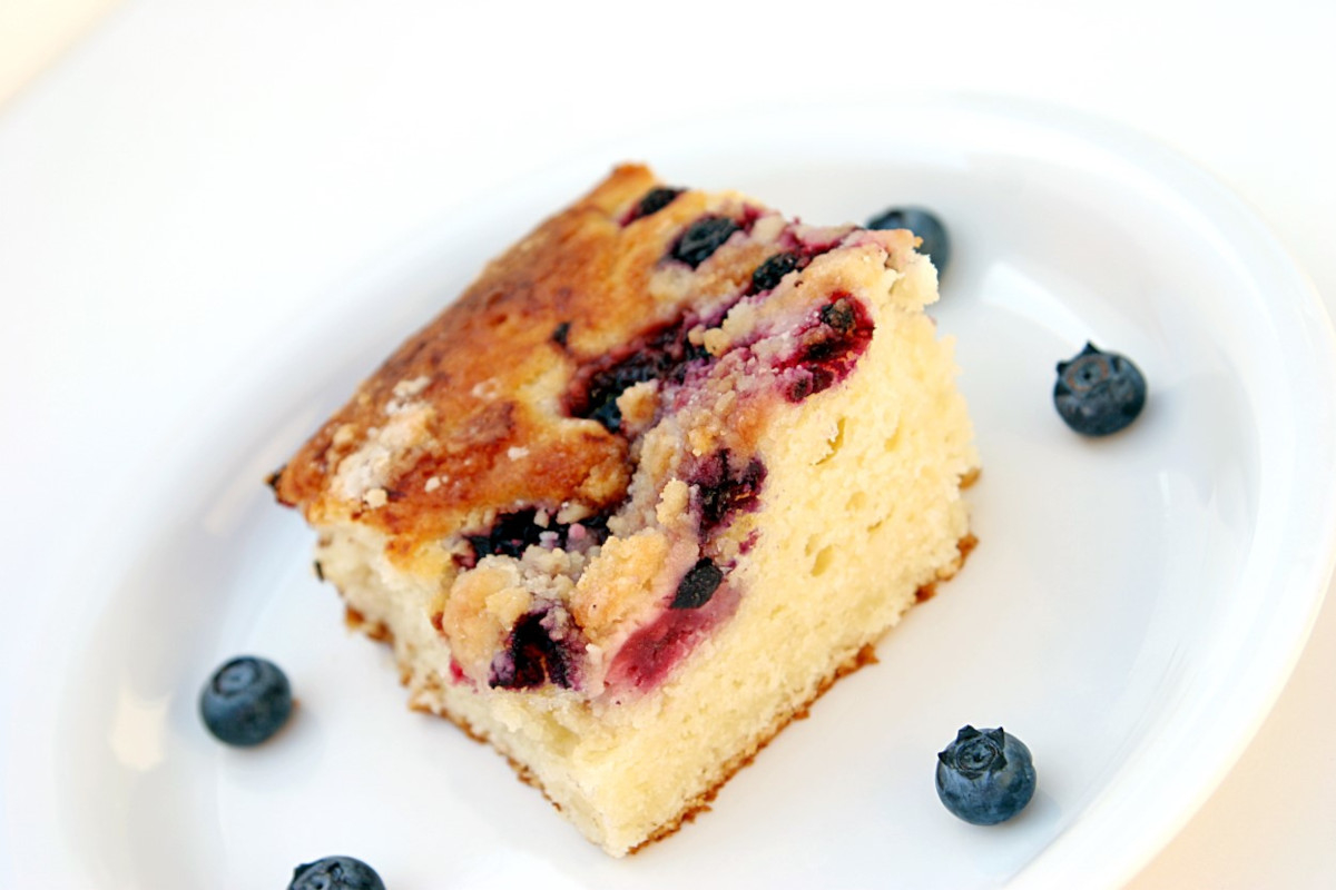 A slice of coffee cake topped with blueberries on a white plate