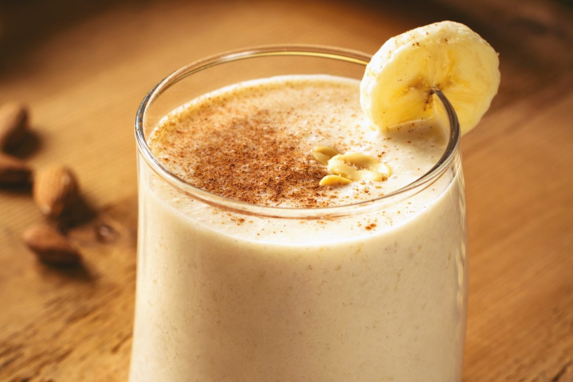 A glass of peanut butter banana smoothie garnished with a banana slice
