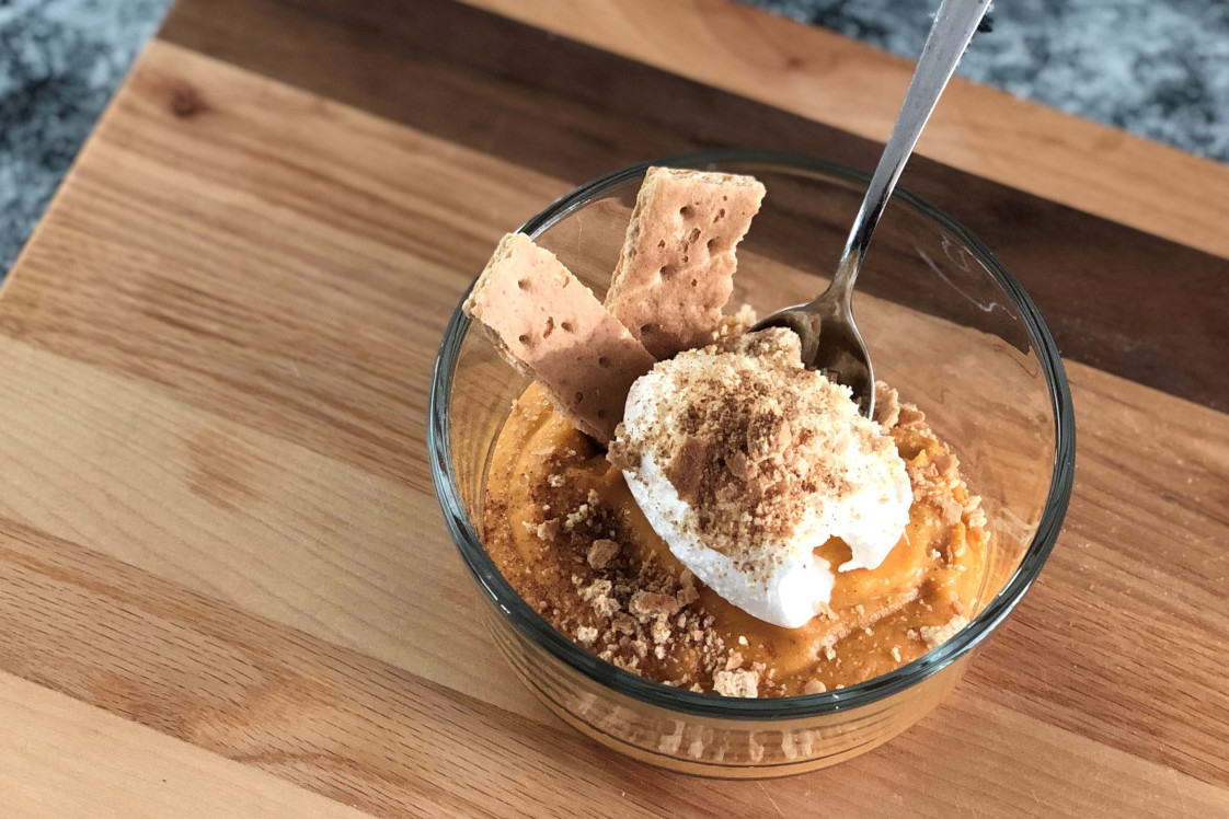 A bowl of pumpkin pudding topped with whipped cream and graham crackers