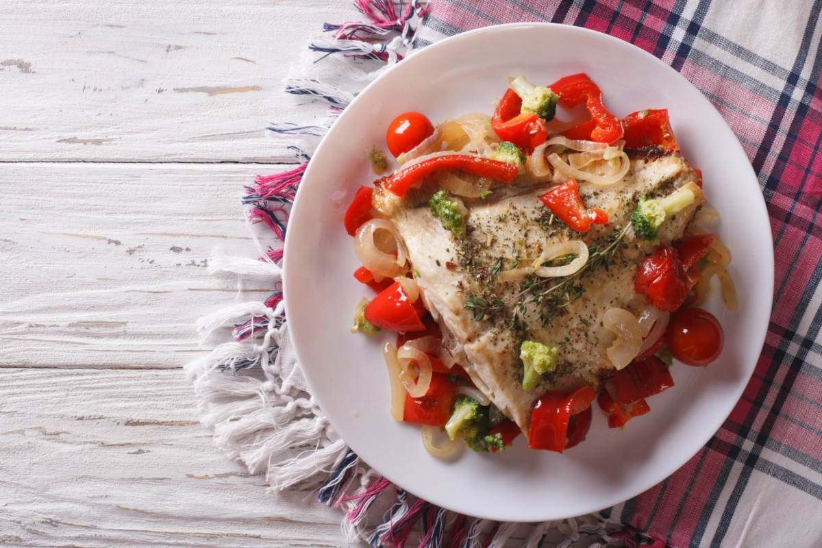 A plate of baked fish with vegetables