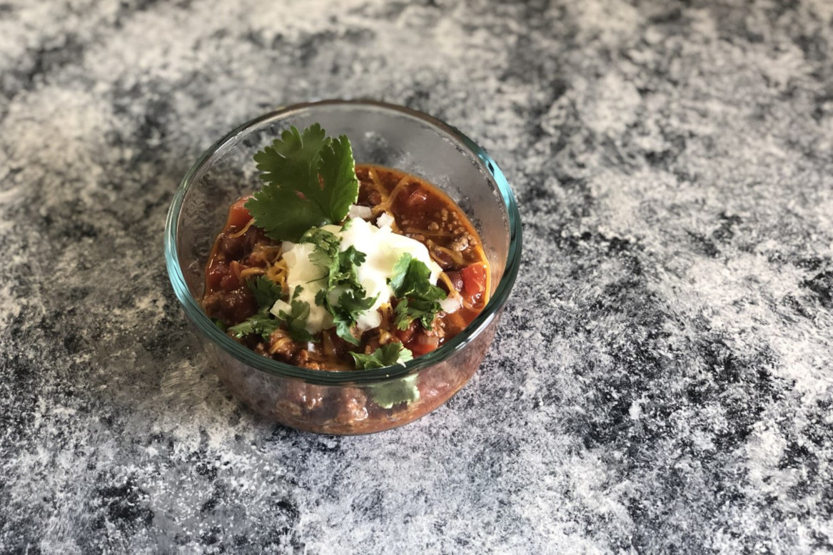 A small bowl of chili topped with sour cream and cilantro