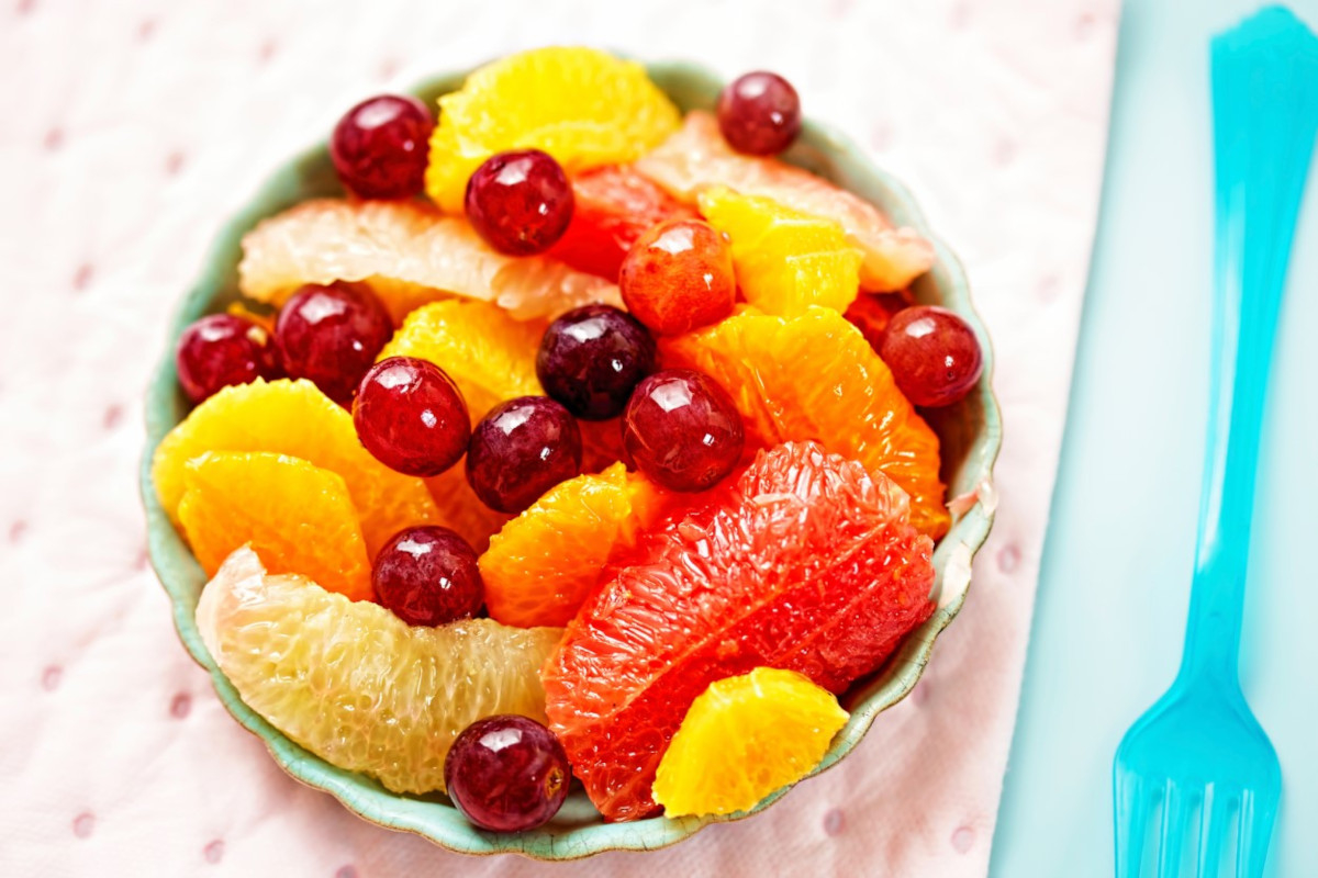 A bowl of citrus fruit with grapes