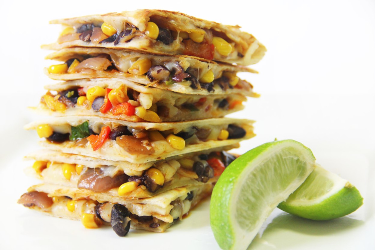 A stack of corn and black bean quesadilla slices with limes