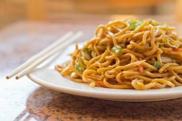 A plate of fried noodles with chopsticks
