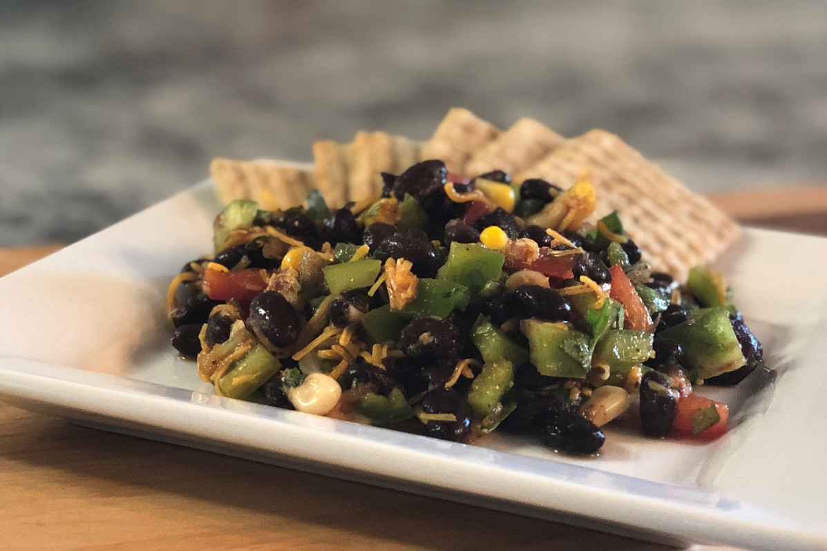 A plate of black bean salad with crackers