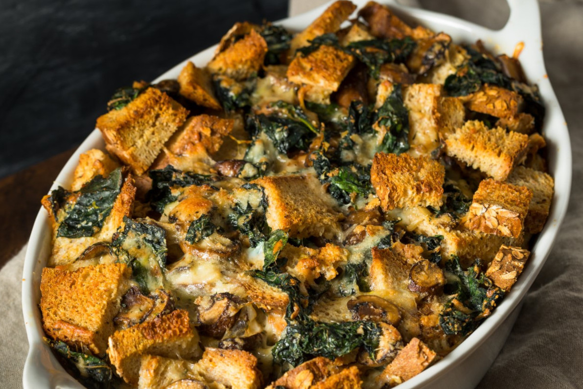 A casserole dish of bread pudding with kale and squash