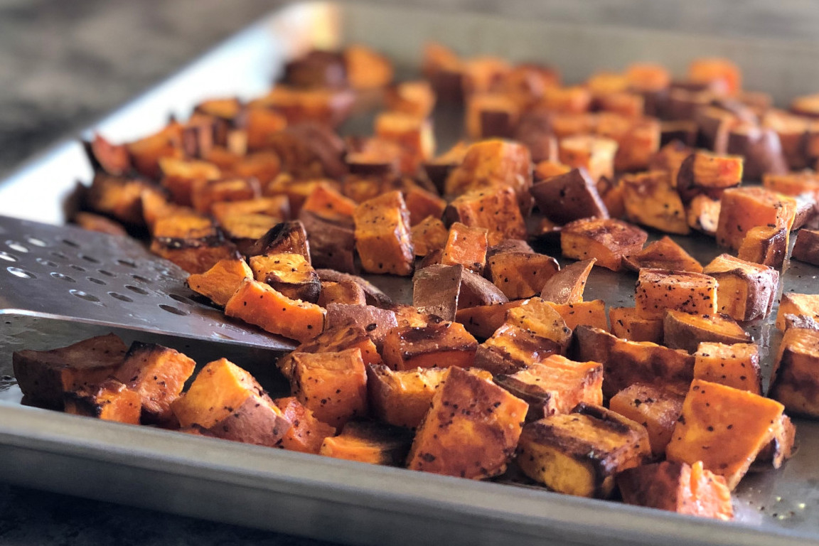 A sheet pan with roasted sweet potato cubes