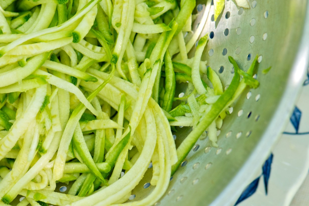 A strainer with shaved strips of zucchini slaw
