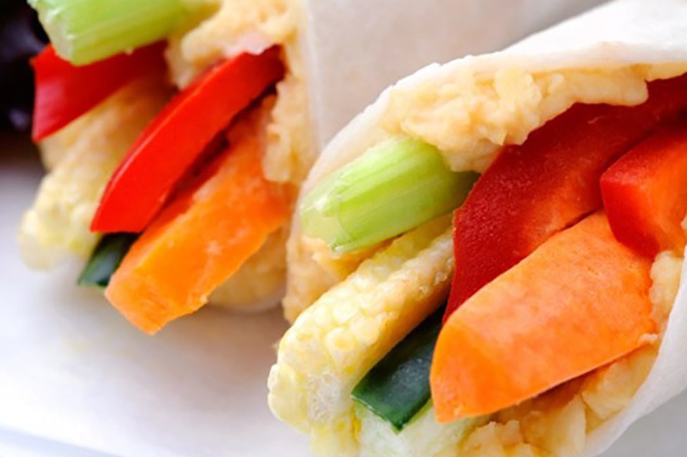 Two veggie rollups with hummus, celery, carrots, red bell pepper and cucumber