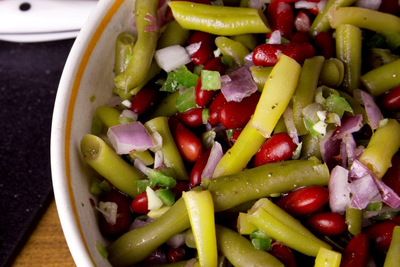 A bowl of marinated three bean salad with wax beans, green beans, kidney beans, red onion and green pepper