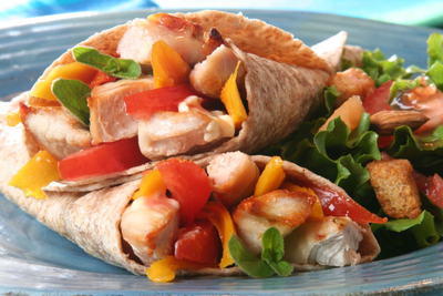 A wrap with chicken, peppers and greens on a blue plate