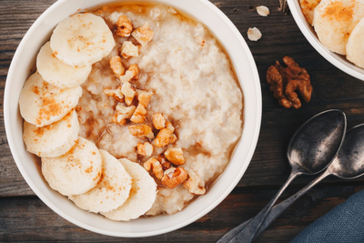 A bowl of oatmeal topped with walnuts and banana slices