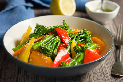 A bowl of broccoli and red and yellow peppers