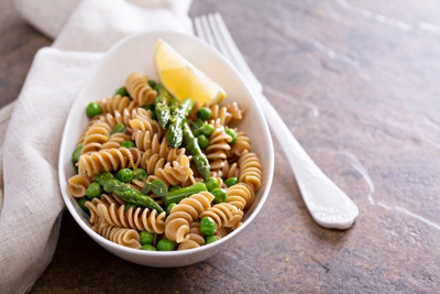 A bowl of rotini with peas and asparagus