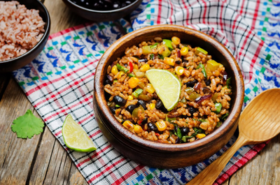 A bowl of rice with beans, veggies and lime