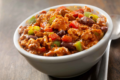 A bowl of chili with meat, beans and peppers