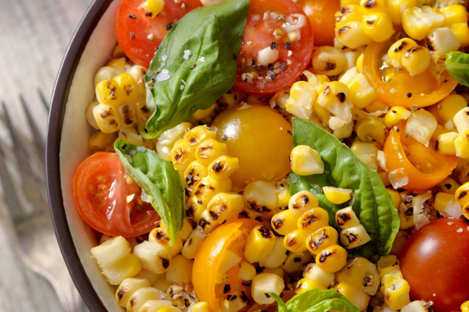 A bowl of grilled corn, basil and cherry tomatoes
