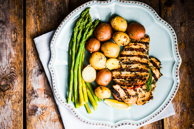 Grilled chicken with potatoes and asparagus on a white plate