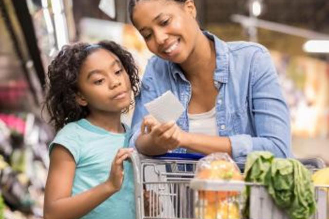 A mother and daughter looking at a shopping list in a grocery store