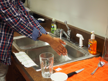 A person washing their hands at a kitchen sink